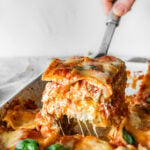 one slice of the mediterranean lasagna pulled out from pan with cheese pull.