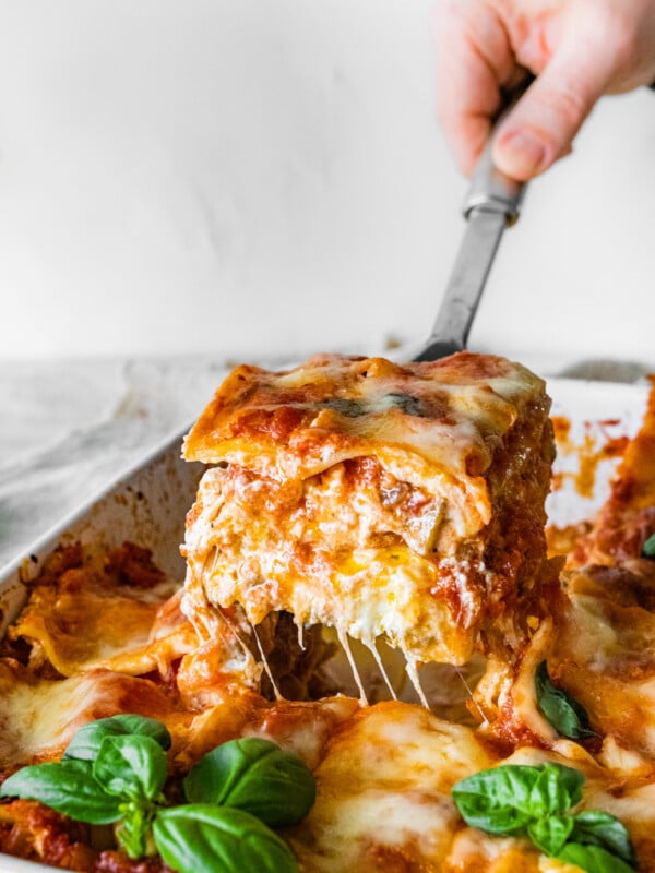 one slice of the mediterranean lasagna pulled out from pan with cheese pull.