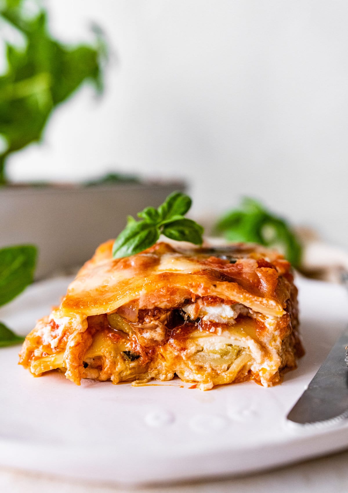 Easy Mediterranean Lasagna slice on a plate ready to eat. Fork and knife on the plate.
