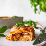 Easy Mediterranean Lasagna slice on a plate ready to eat. Fork and knife on the plate.