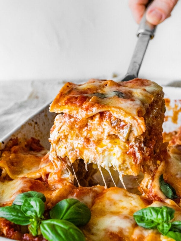 Spatula lifting a slice of Mediterranean lasagna from a pan.
