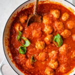Process for making Italian Sausage Meatballs Recipe (In Sauce)- cooked meatballs in sauce with added basil on top.