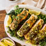 Chilean sea bass on a tray with greenery and lemon slices.