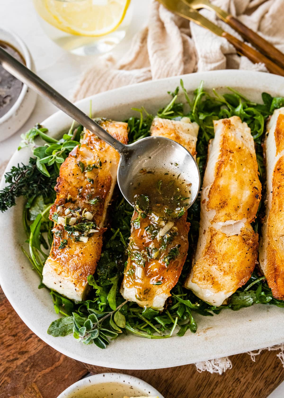 How to make pan seared chilean sea bass process: spponing sauce over cooked sea bass.