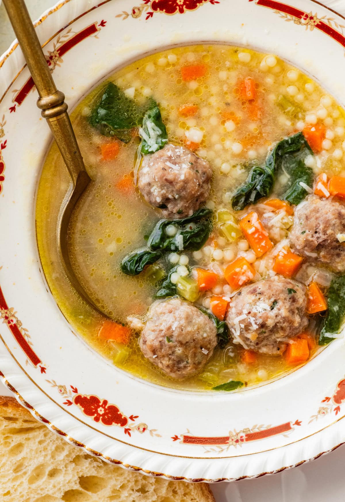 A bowl of homemade Italian wedding soup with a spoon resting in the bowl.