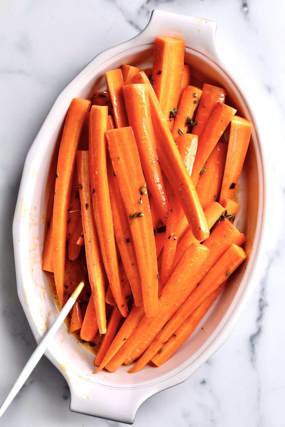 How to makeBest Honey Glazed Carrots Recipe (Oven Roasted)- carrots tossed in glaze in a bowl.