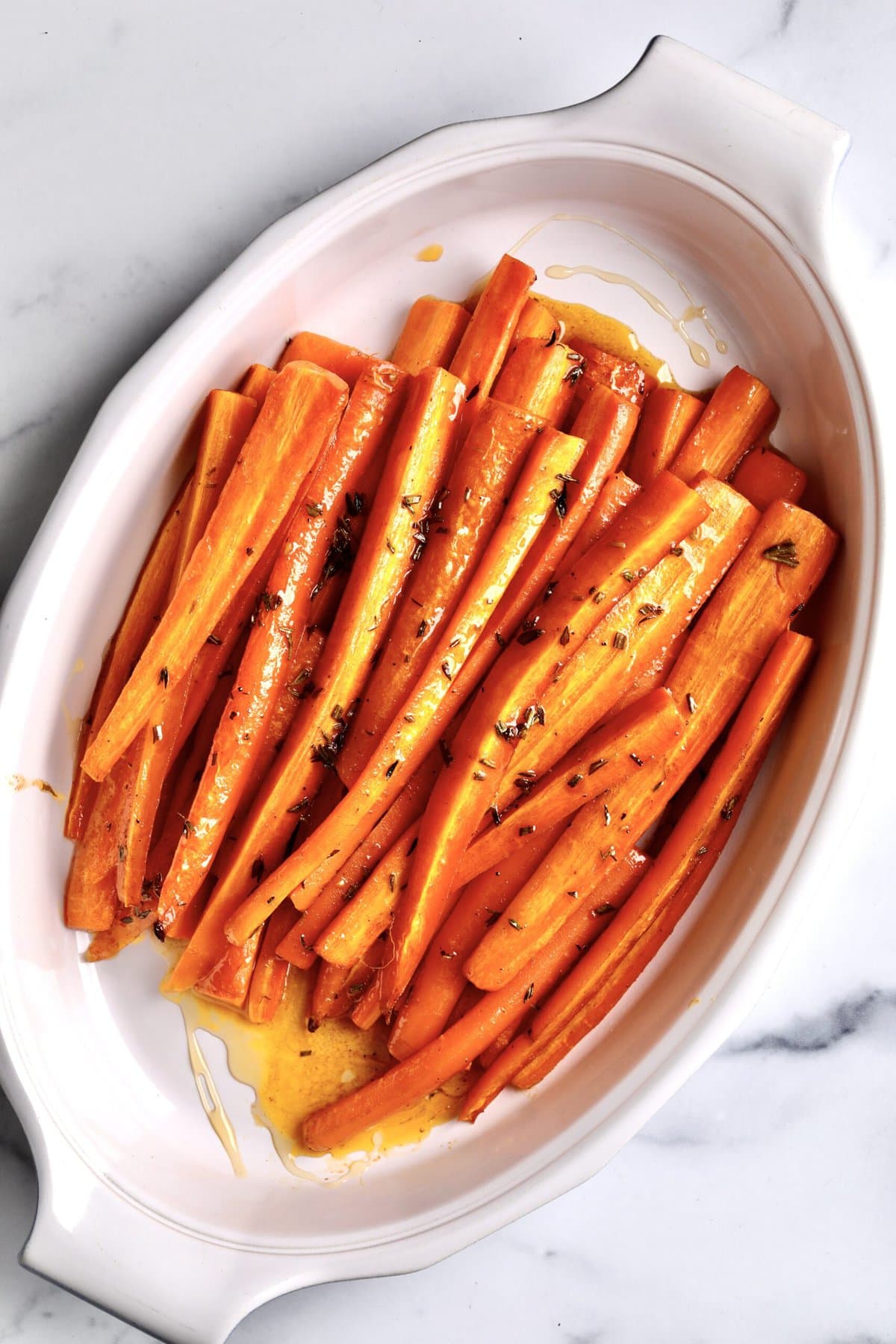 Best Honey Glazed Carrots Recipe (Oven Roasted) in a white serving plate. The carrots are roasted and ready to serve. 