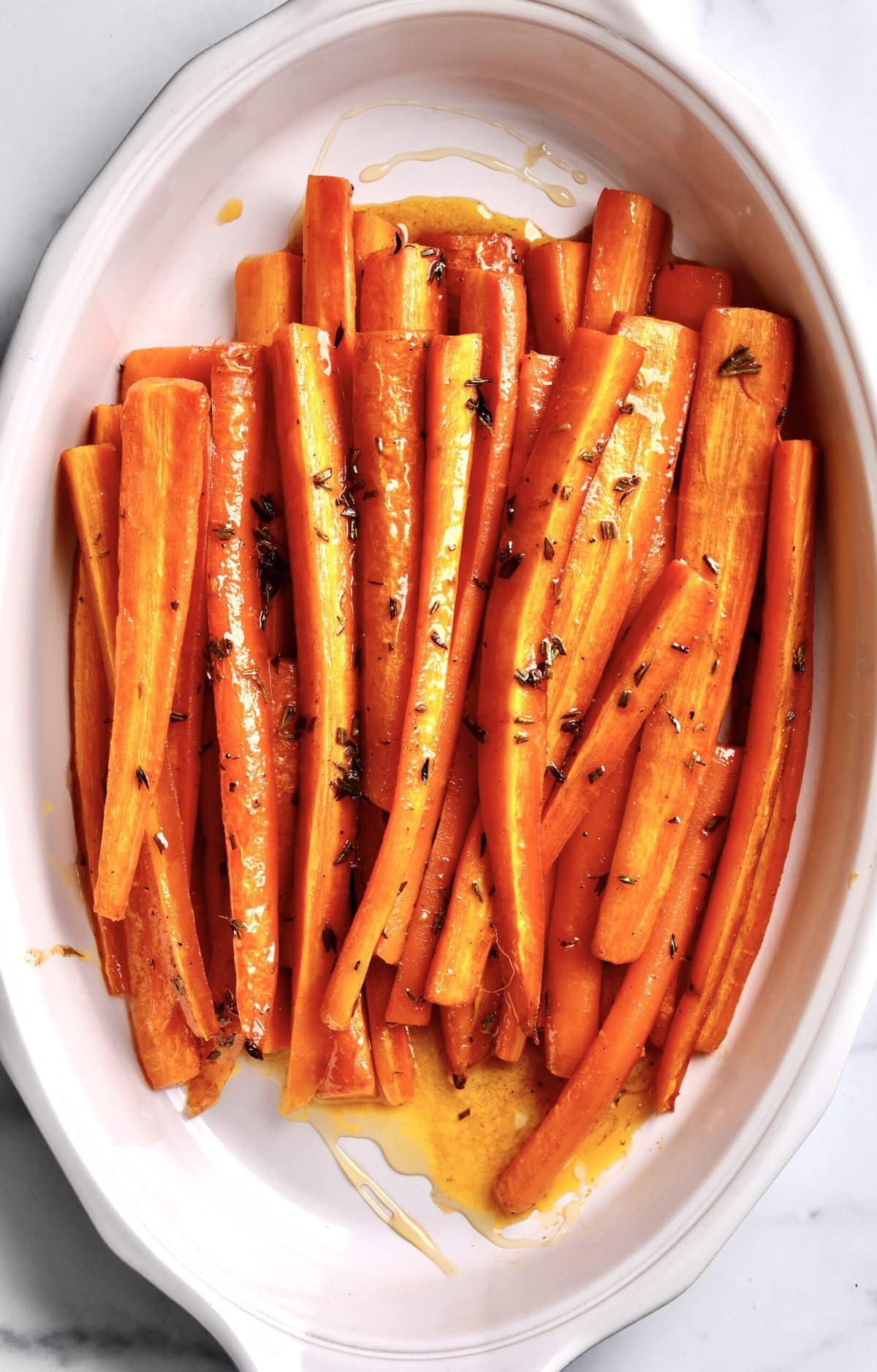 Best Honey Glazed Carrots Recipe (Oven Roasted) in a white serving plate. The carrots are roasted and ready to serve.