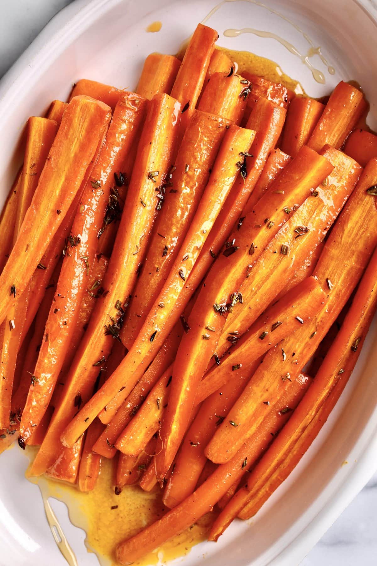 Best Honey Glazed Carrots Recipe (Oven Roasted) in a white serving plate. The carrots are roasted and ready to serve.