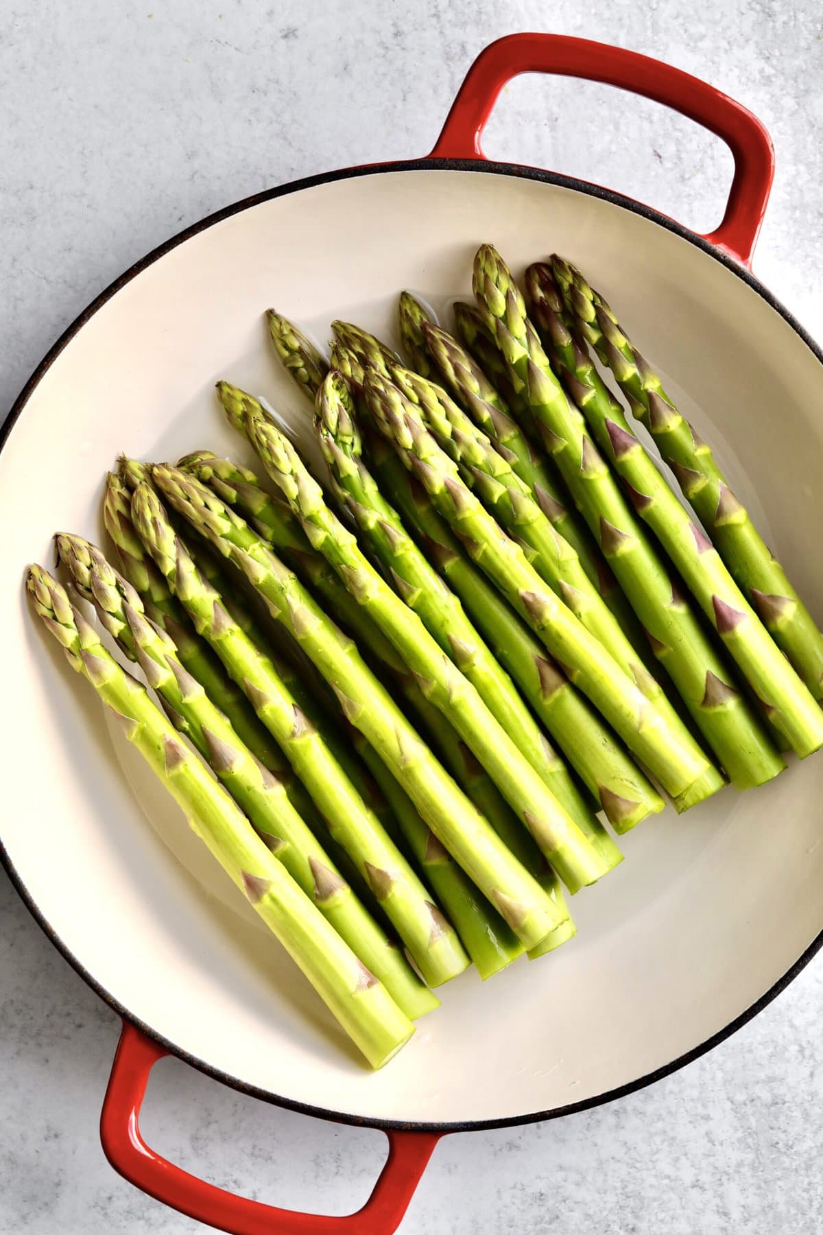 How to make simple steamed asparagus recipe: raw asparagus ready to steam in a shallow pot.
