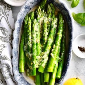 Steamed asparagus in a blue and white oblong bowl.