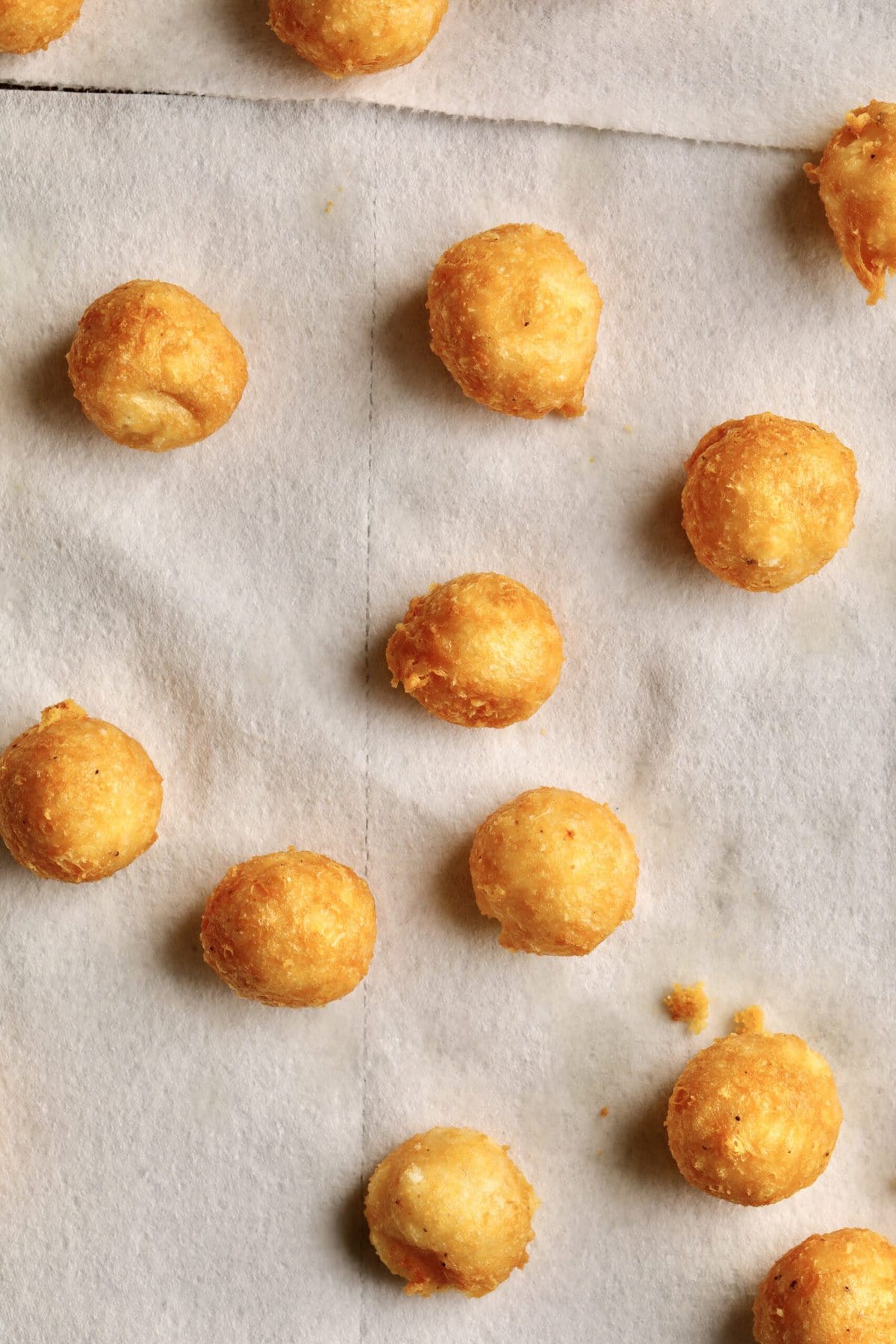 Process for making fried cheese balls-letting cheese balls rest on paper towels to absorb excess oil.