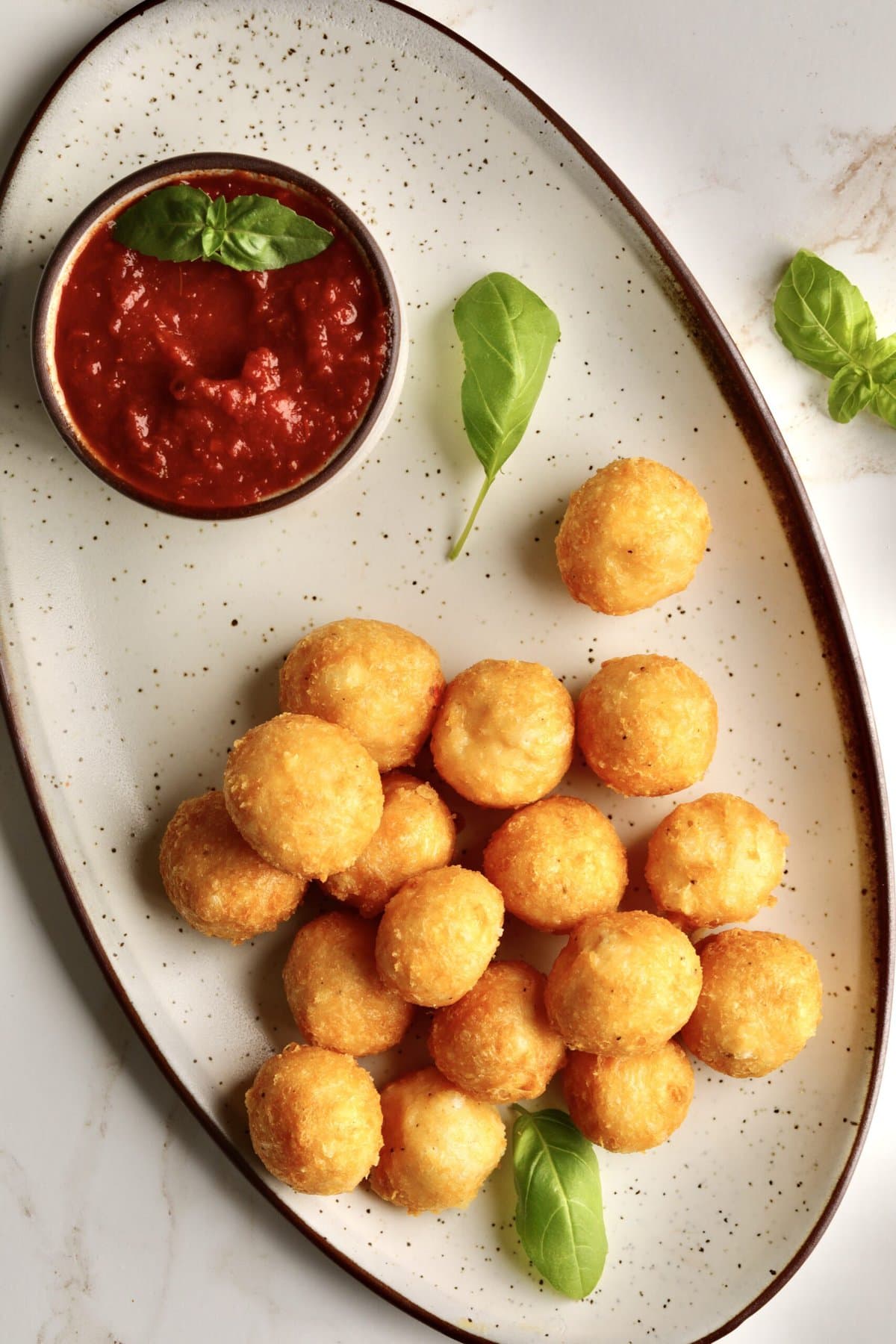 Easy Fried Cheese Balls Recipe (Crispy Bites)- on a serving platter with tomato sauce for dipping.