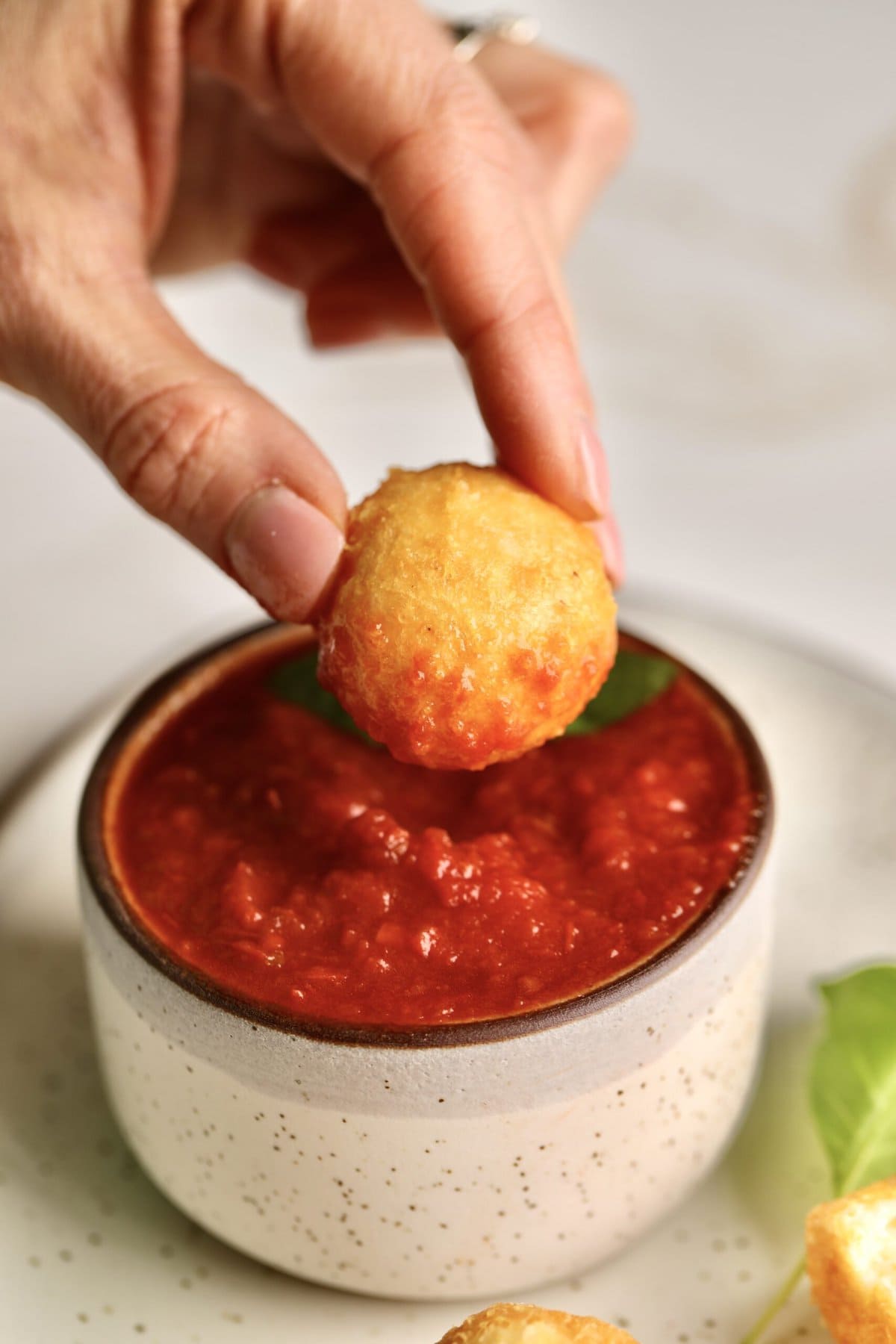 dipping the Easy Fried Cheese Balls Recipe (Crispy Bites) in the tomato dipping sauce.