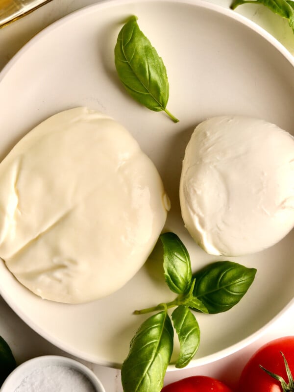 Balls of burrata and mozzarella in a bowl with basil.