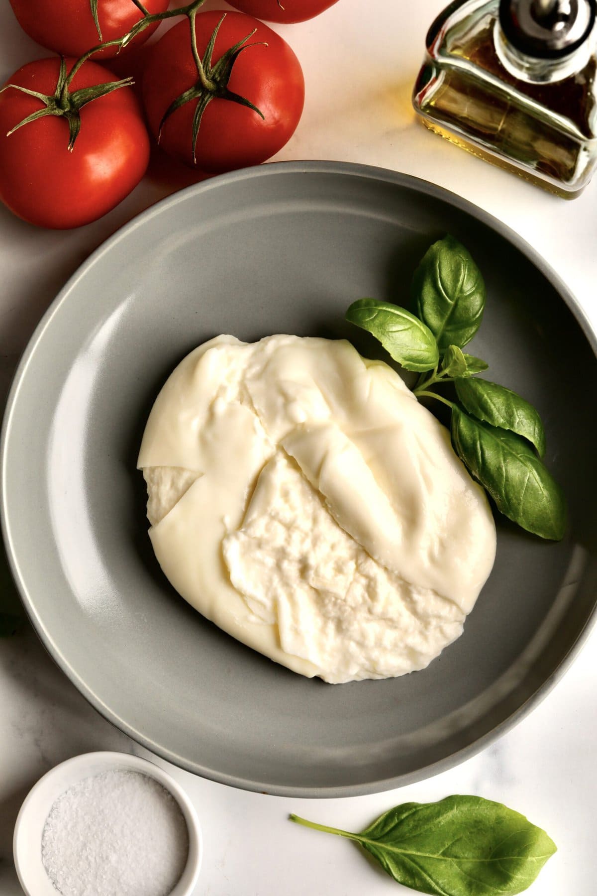 burrata cheese on a plate cut open to see the creamy interior.