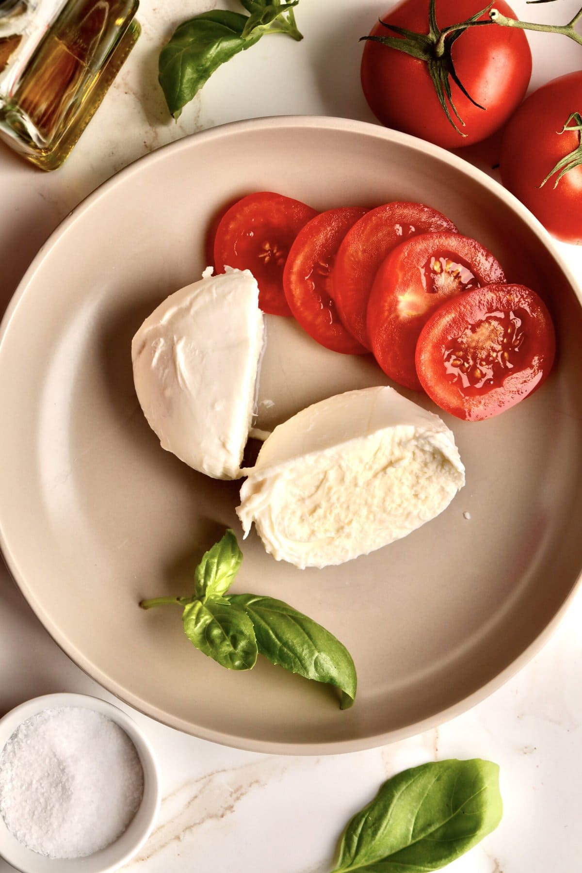 mozzarella cheese cut in half on a plate with slices of tomatoes.