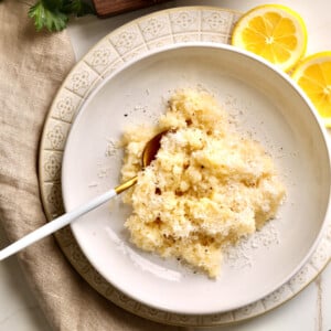 Spoon on a white plate with creamy parmesan rice.