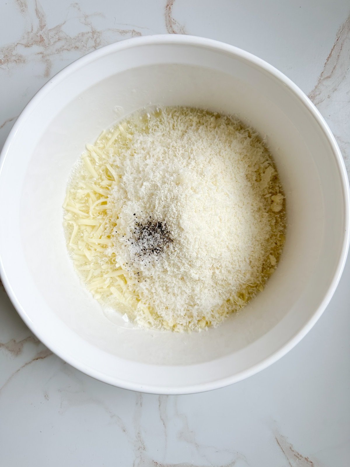 Process for making fried cheese balls- mixing all cheese and salt and pepper in a bowl.