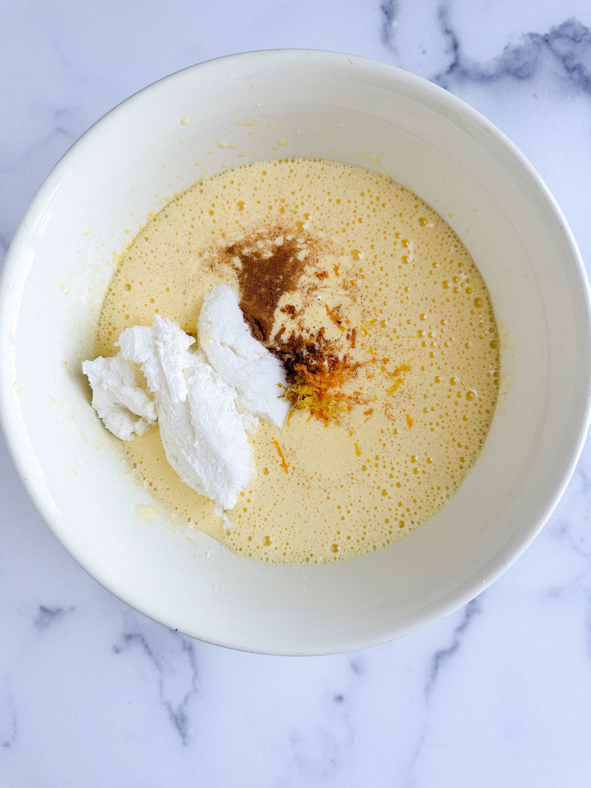 adding ricotta, zest, and spices, to the egg and sugar mixture.