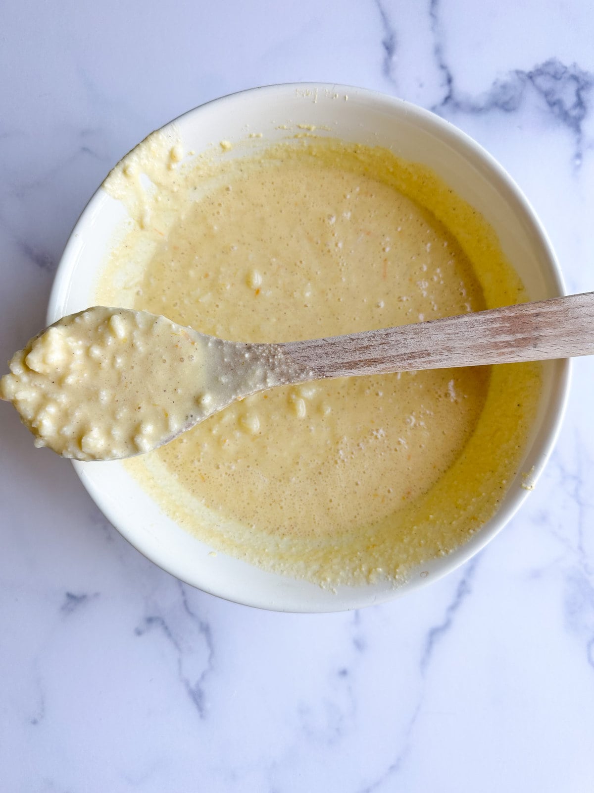 Adding rice to the egg and ricotta mixture in a mixing bowl. Mix until combined with wooden spoon.