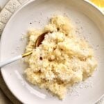 creamy rice on a plate with butter in the middle and extra cheese on top.