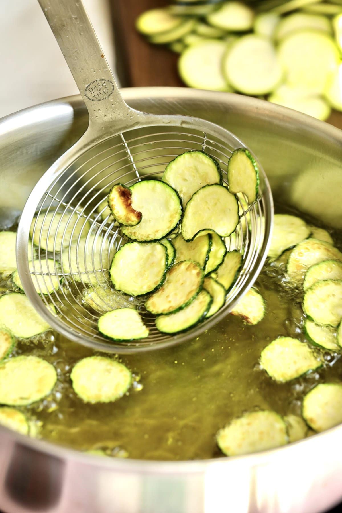 process for how to make spaghetti alla nerano- removing the zucchini from hot oil with a slotted spoon.