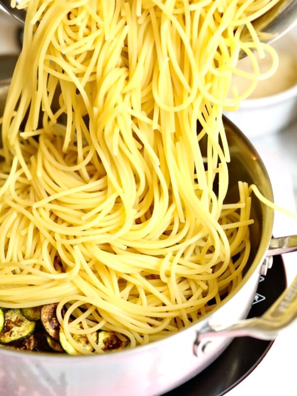 process for how to make spaghetti alla nerano- adding al dente pasta to the pan with fried zucchini and oil.