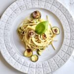 plate of Spaghetti alla Nerano Recipe (Fried Zucchini Pasta) on a plate with a basil leaf on the top.