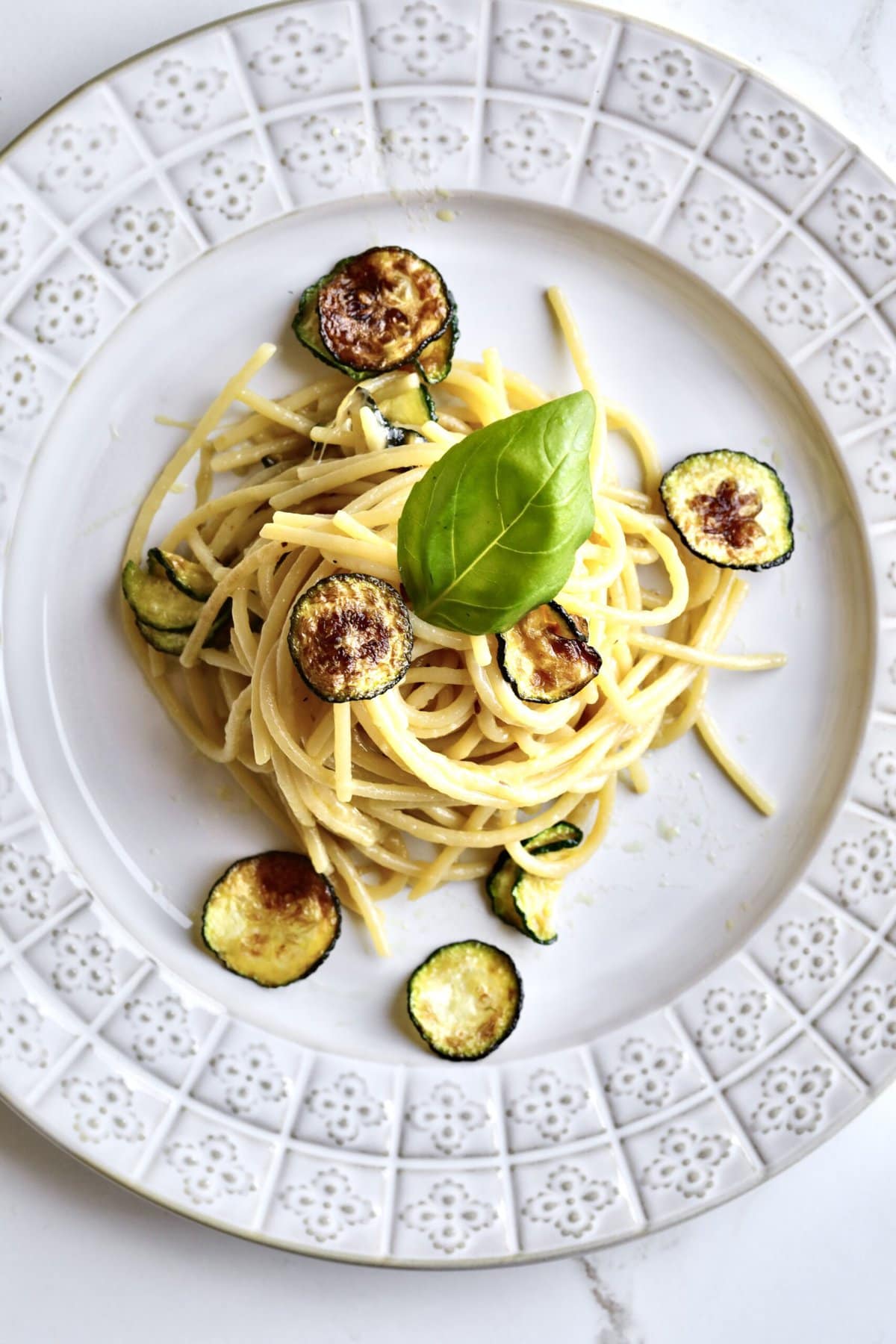 plate of Spaghetti alla Nerano Recipe (Fried Zucchini Pasta) on a plate with a basil leaf on the top.