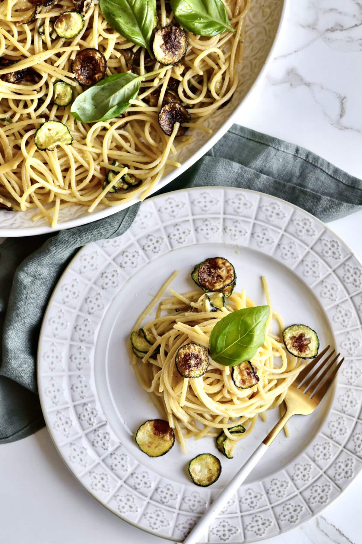 Spaghetti alla Nerano on a plate with a platter of the final dish.