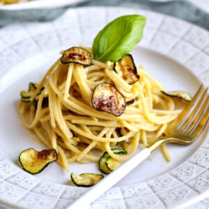 Spaghetti alla nerano on a white plate with a fork.