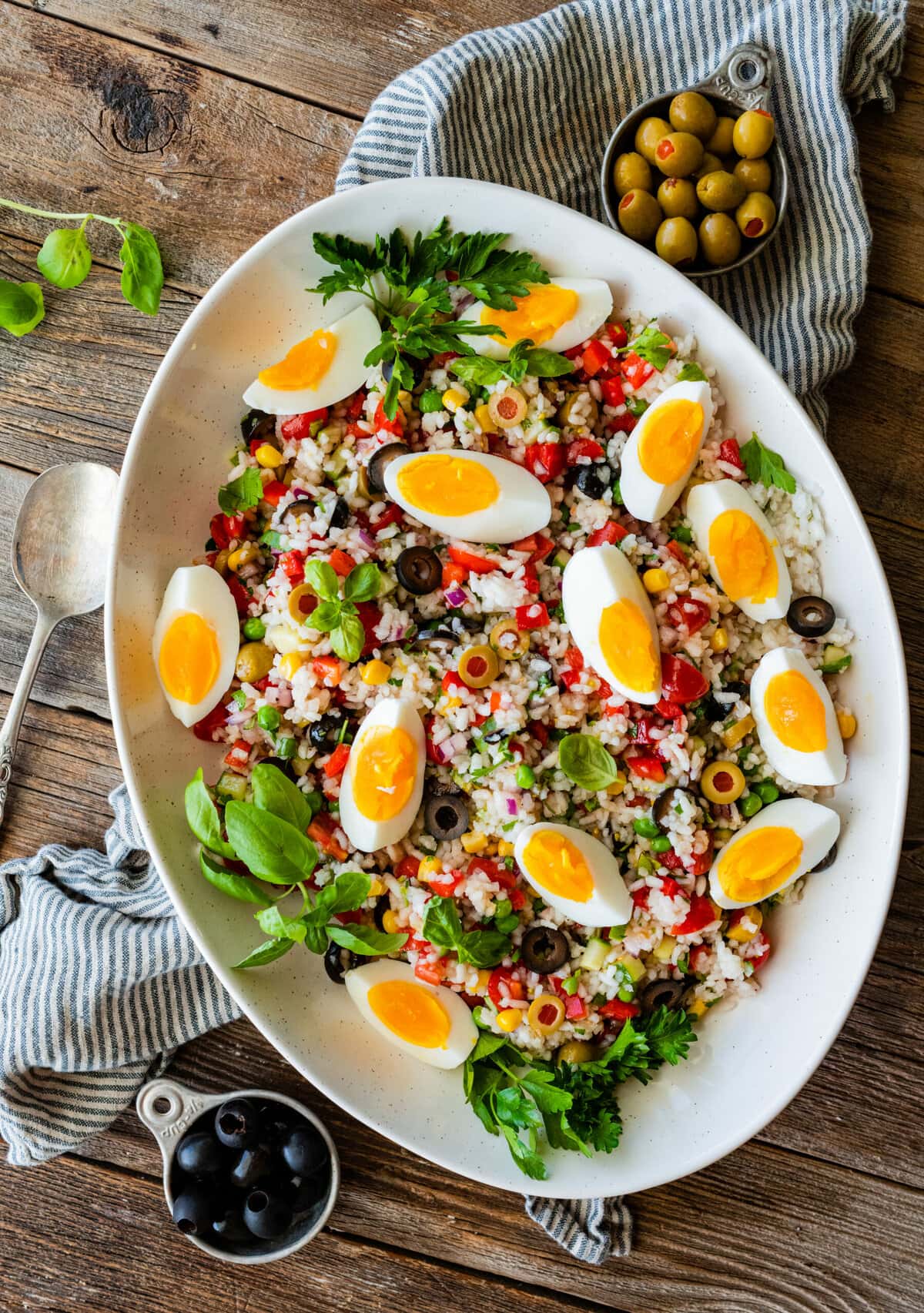 Large serving bowl of Italian rice salad topped with sliced hard boiled eggs.