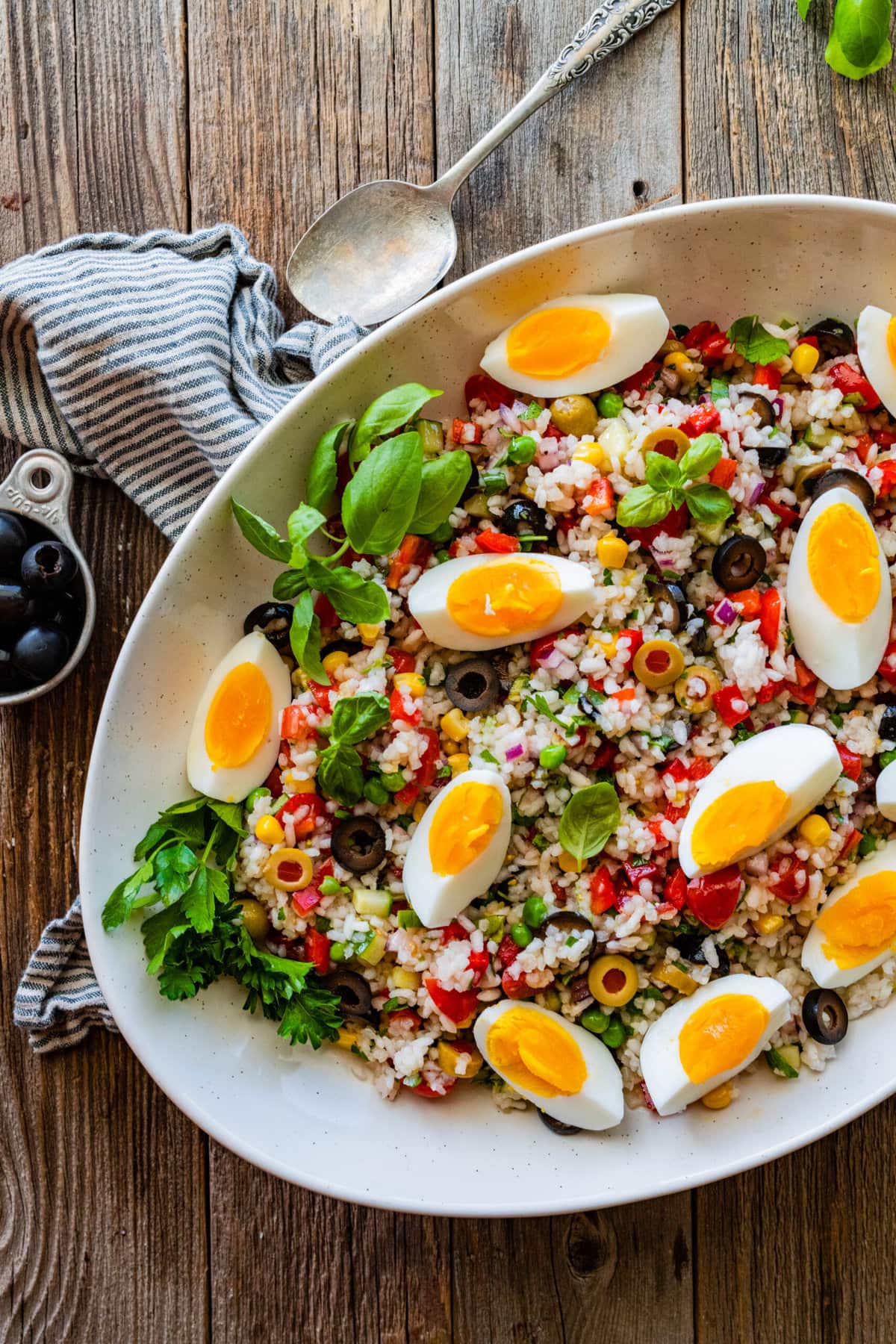 Easy Italian rice salad (insalata di riso) in a large platter with the hard boiled eggs sliced on top.