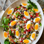 Easy Italian rice salad (insalata di riso) in a large platter with the hard boiled eggs sliced on top.