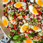 Easy Italian rice salad (insalata di riso) in a large platter with the hard boiled eggs sliced on top.