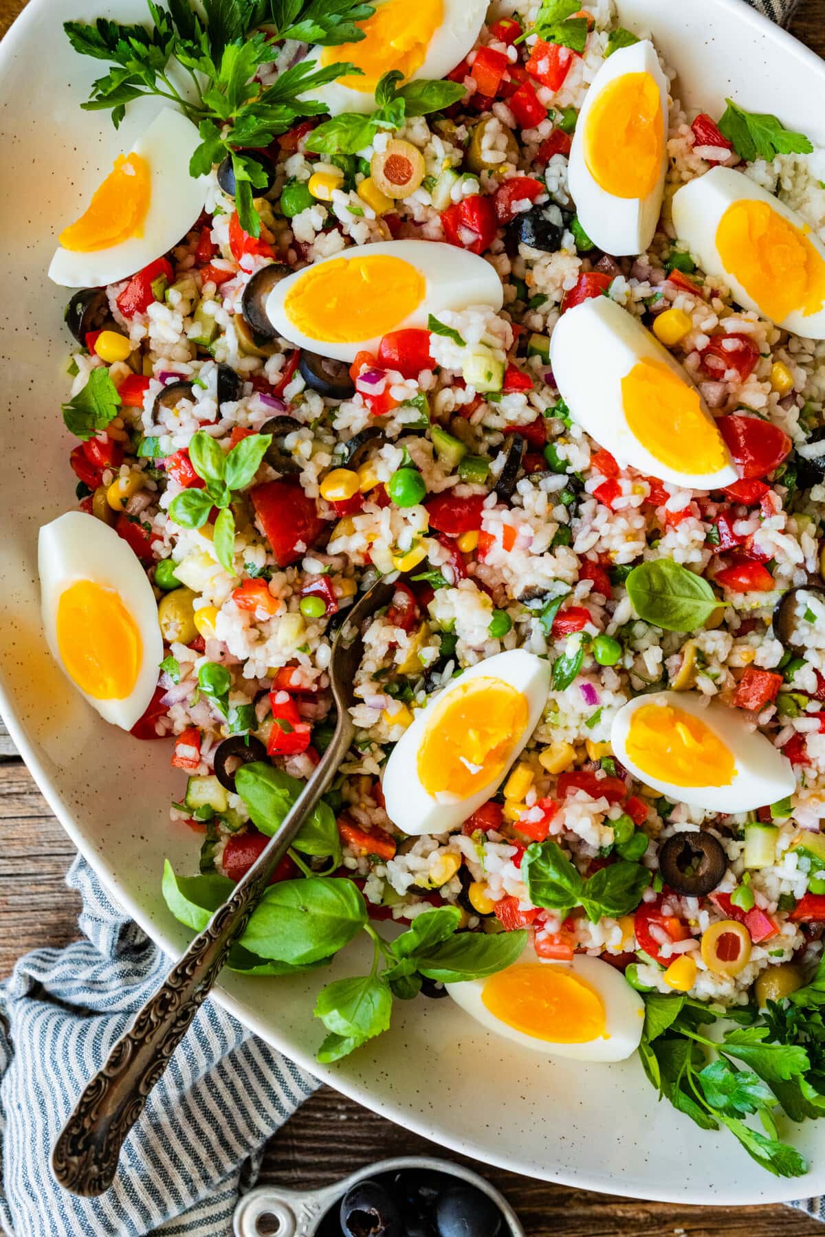 Easy Italian rice salad (insalata di riso) in a large platter with the hard boiled eggs sliced on top.