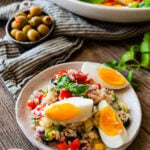 Italian rice salad on a plate with a platter of the rice salad in the background.