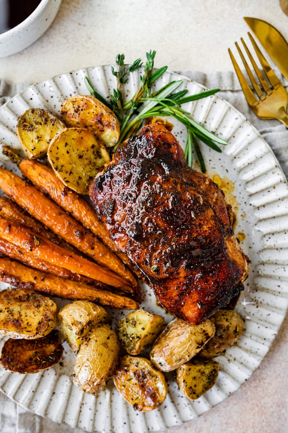 cooked thick pork chops on plate with potatoes and carrots.