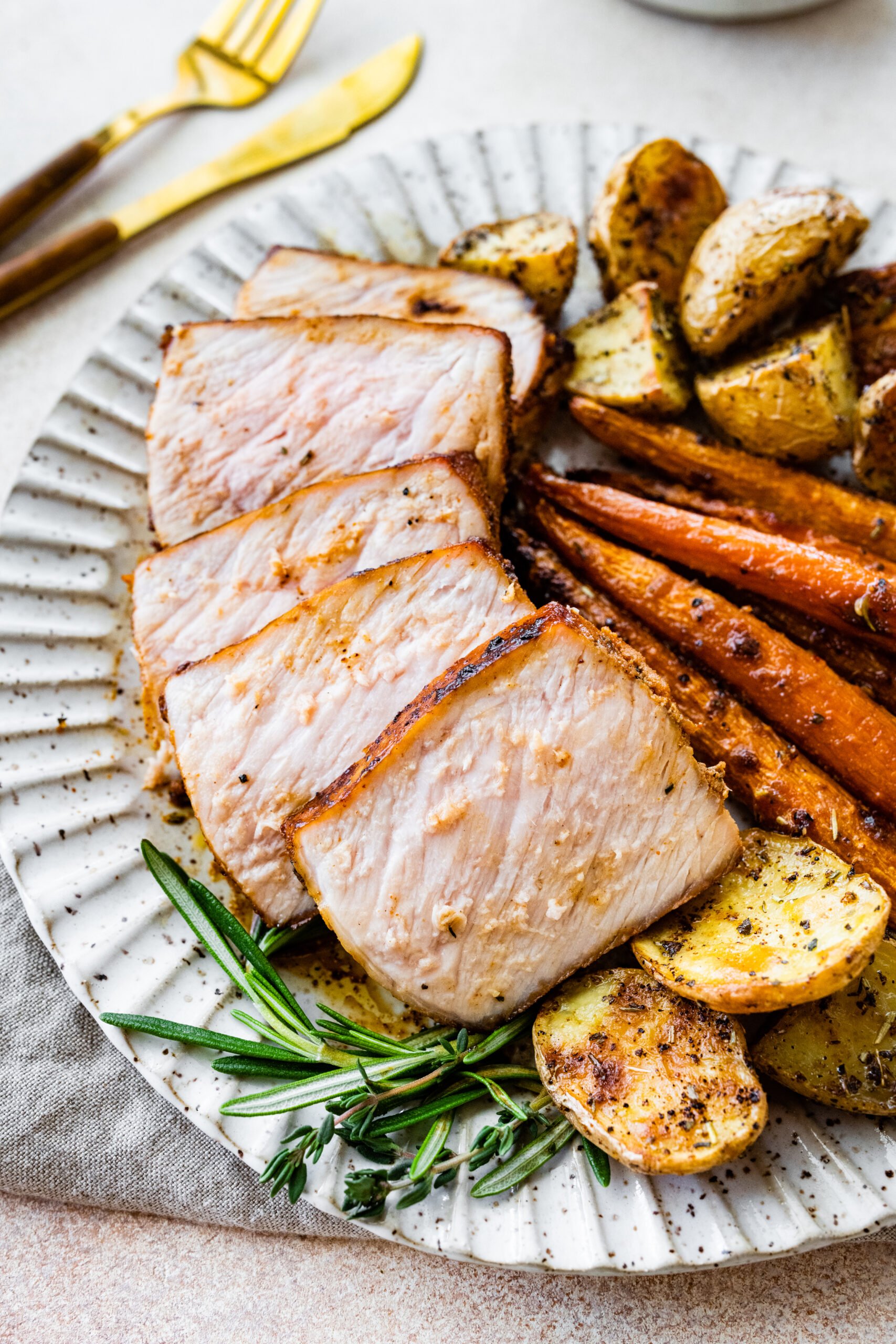 Lots of thick pork chop slices on a plate with potatoes and carrots.