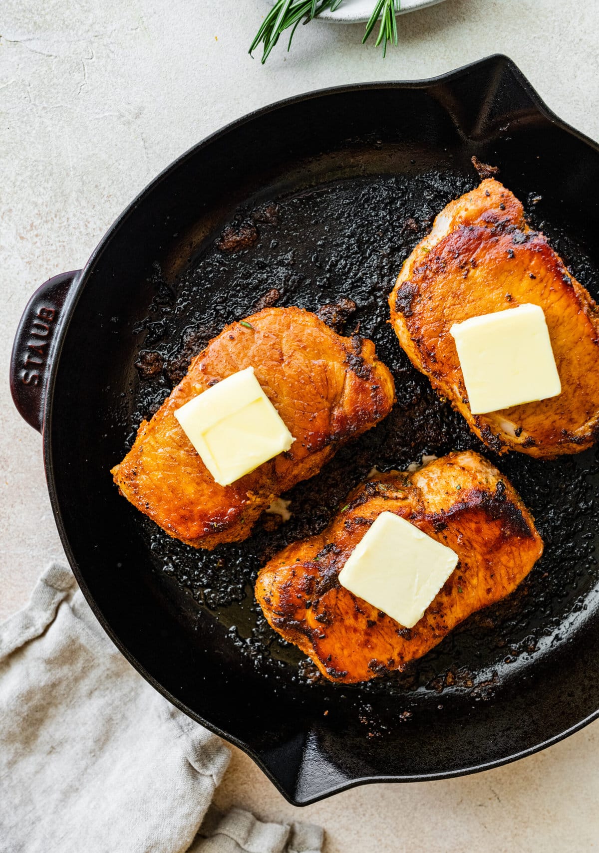 Step-by-step photos for How to cook thick pork chops- sear both sides of the pork chops and add a pat of butter to each.