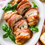 How to make Mozzarella stuffed Chicken chicken- finished stuffed chicken cut in slices and served on a white platter with fresh basil.
