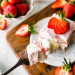 Fork with a bite from a slice of strawberry tiramisu.