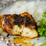 Blackened cod on a white place with rice and greens