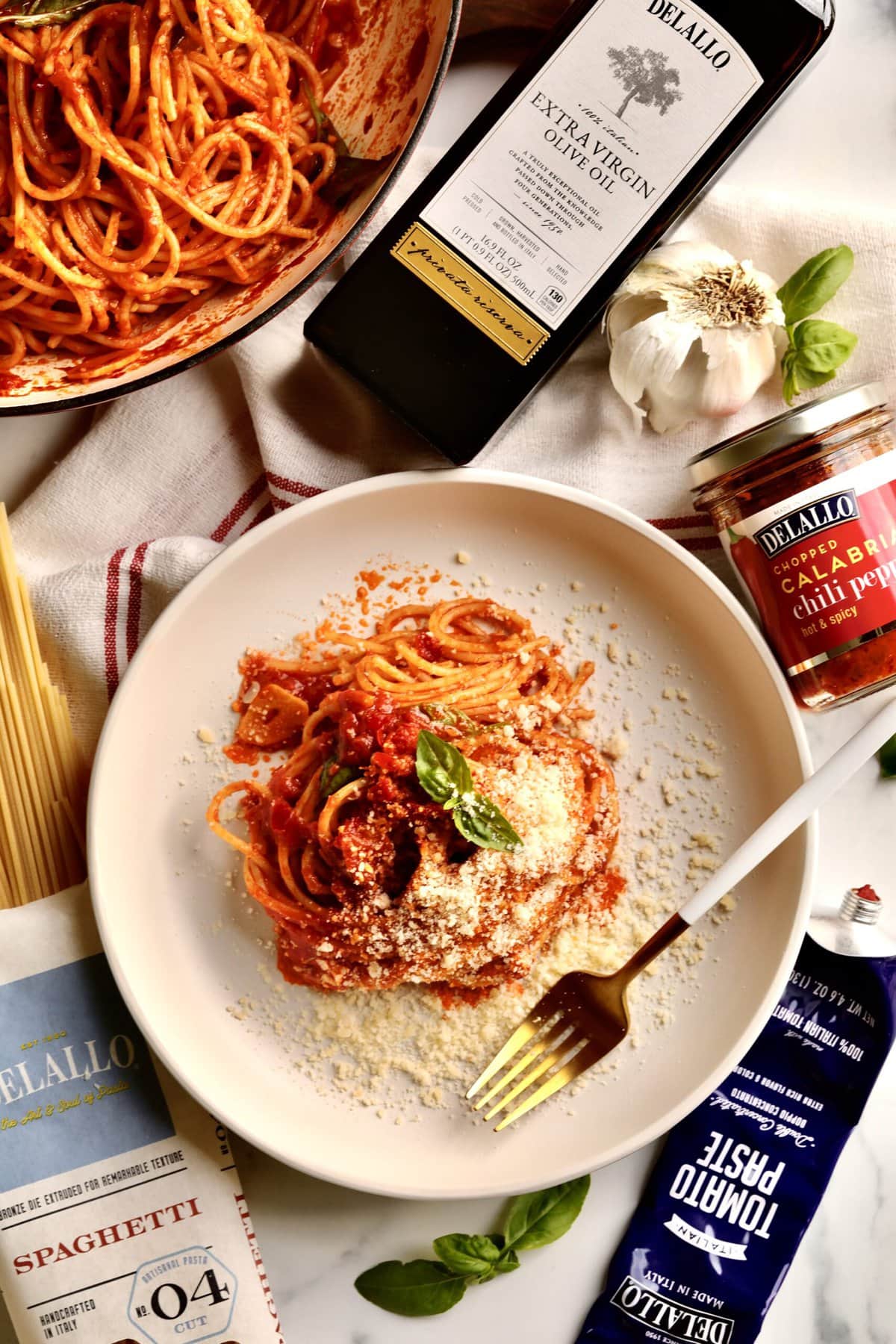 Quick Tomato Paste Pasta Sauce Recipe with Spaghetti on a plate. All the products and ingredients surround the plate of spaghetti.
