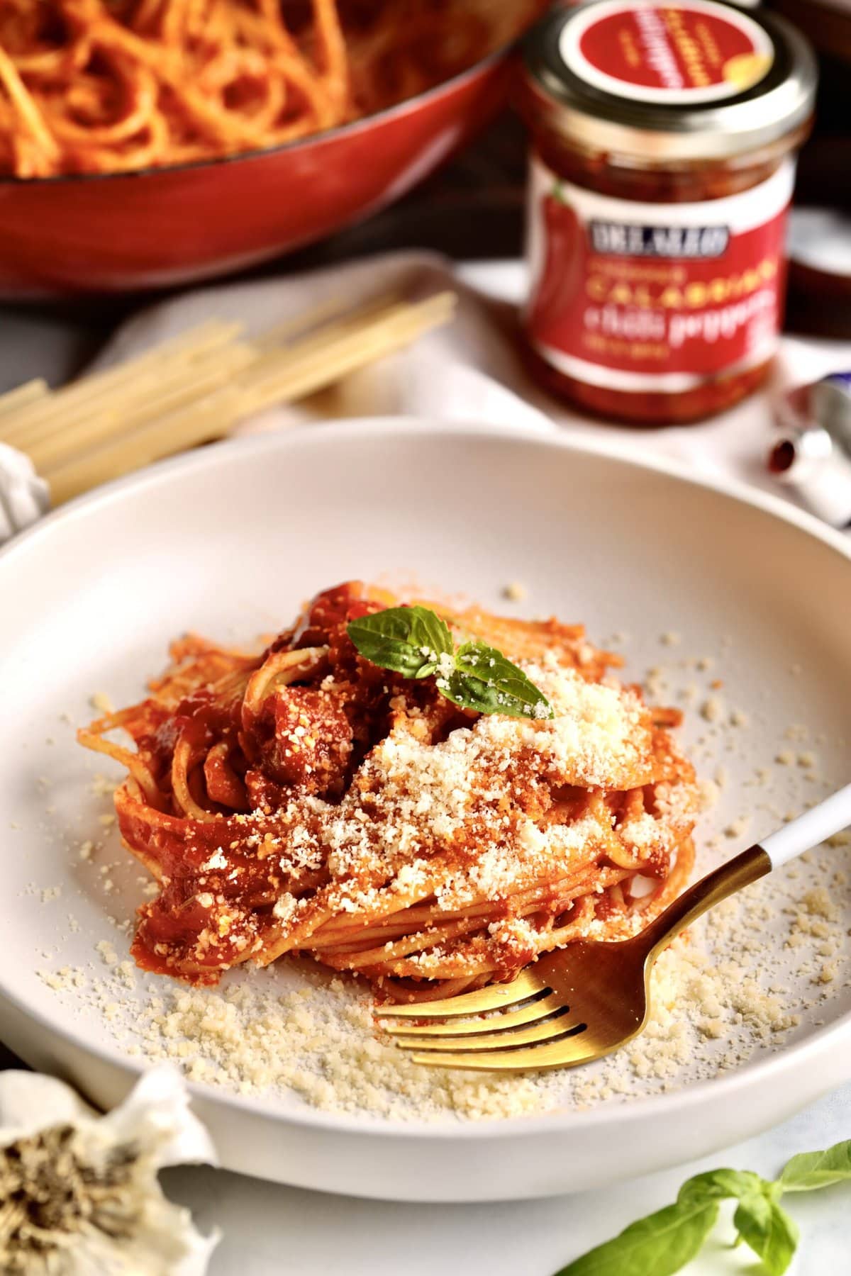 Fork on a plate with pasta topped with tomato paste sauce.