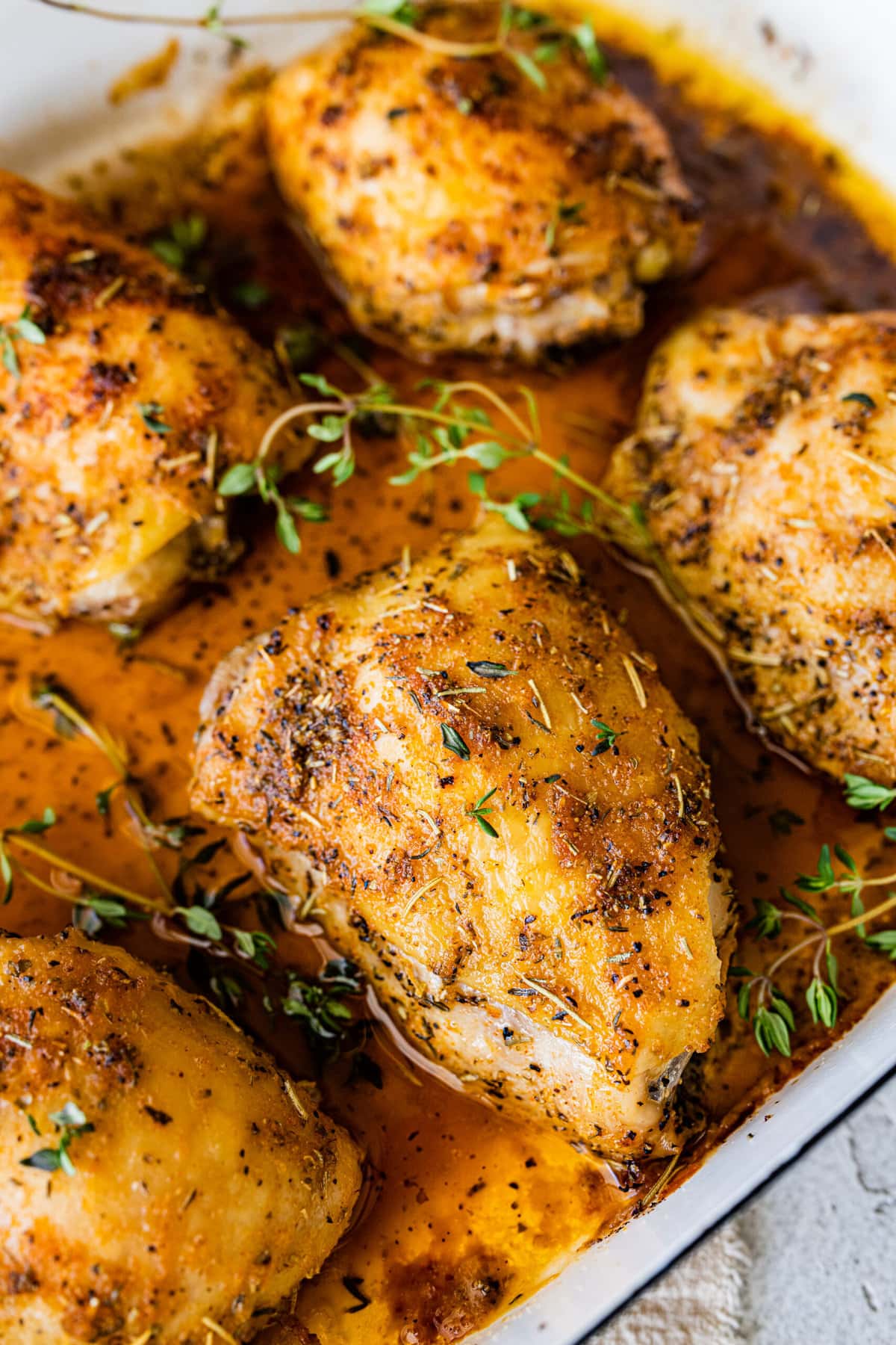 How Long to Bake Chicken Thighs at 375 (Best Recipe)- baked chicken in a pan with pan juices. Fresh herbs on top.