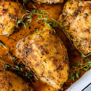 How Long to Bake Chicken Thighs at 375 (Best Recipe)- baked chicken in a pan with pan juices. Fresh herbs on top.
