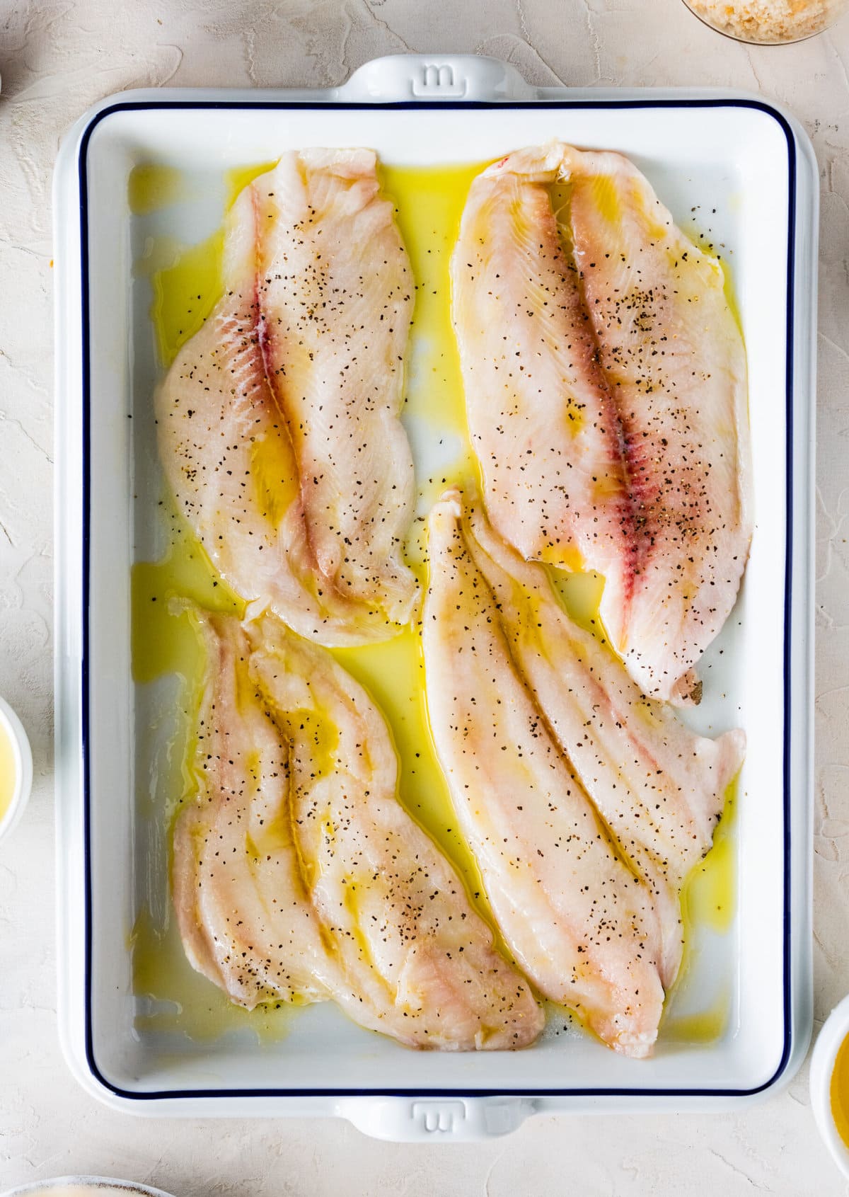 How to make-Baked Flounder Recipe with Lemon Butter Garlic Sauce- adding the fish to the pan with olive oil.