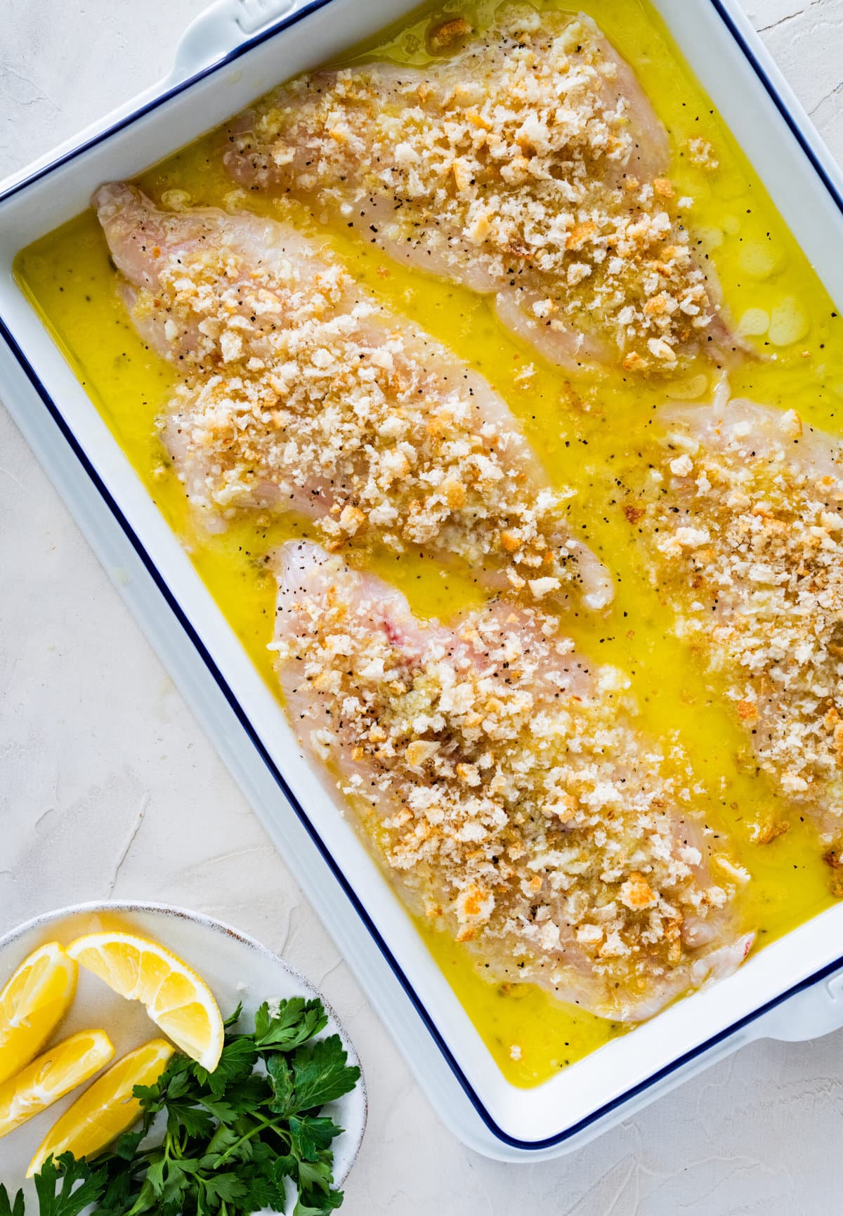 Baked Flounder Recipe with Lemon Butter Garlic Sauce- fish with sauce before baking in the oven. Adding homemade breadcrumbs on top.